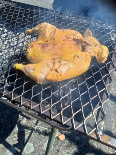 Poulet grillé sur un barbecue, avec une marinade dorée et fumée.
